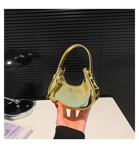 Close-up of golden mirror-finish patent leather handbag in a modern crescent shape