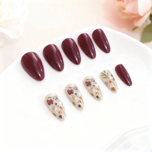 Long almond press-on nails in deep burgundy and floral white with glossy finish