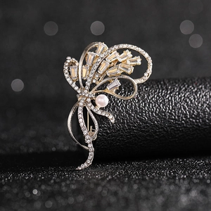 Detailed view of elegant gold brooch with sparkling rectangular zircons and a white pearl