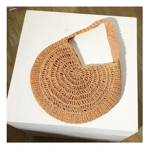 Detailed macro view showing texture of the beige woven straw shoulder bag on white stand