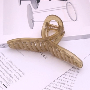 Elegant amber translucent large shark hair claw clip displayed on an open book