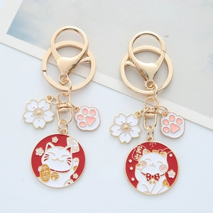 Close-up of golden Maneki Neko keychains with cherry blossom and cat paw charms