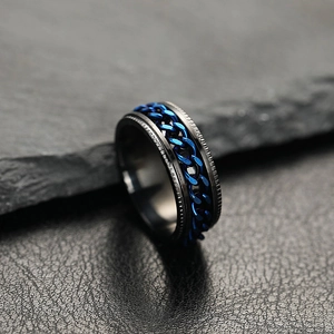 Matte black stainless steel spinner ring with blue chain inlay for men on dark stone