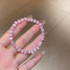 Detail of pink cat-eye stone beaded bracelet showcasing glossy texture and smooth beads