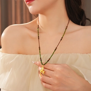 Detail of vintage tiger eye horse pendant on braided cord necklace worn by a model