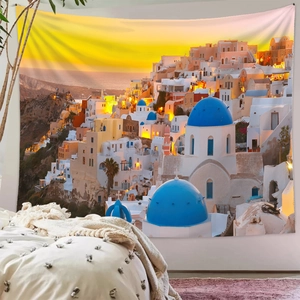 Detailed Santorini sunset wall tapestry featuring blue domes in a cozy bedroom setting