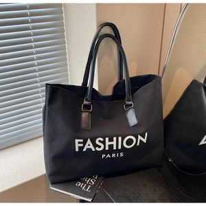 Detail einer großen schwarzen Canvas-Tasche mit Fashion Paris-Print auf einem Holztisch