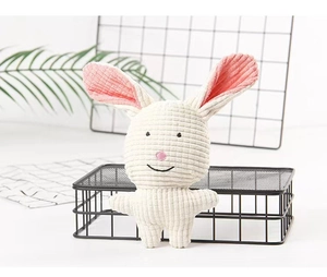 Detail of white corduroy plush dog toy with pink ears and cute embroidered bunny face
