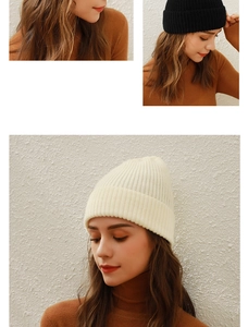 Close-up of the soft knitted texture and cuffed brim of the black and beige beanies