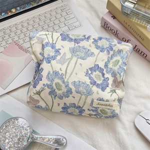 Detail of floral makeup bag with blue flowers, butterfly prints and leather brand tag