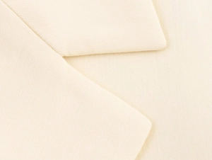 Close-up of beige blazer lapel showing high-quality wool texture and clean stitching