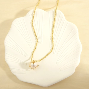 Detail view of a gold necklace with a pearl pendant and small diamonds on shell tray