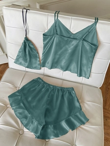 Detailed shot of teal satin sleepwear set featuring V-neck camisole and ruffled shorts