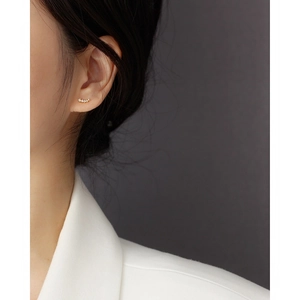 Close-up of a delicate gold S925 silver stud earring with crystals on a female model