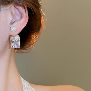 Close-up of 18k gold plated earring with round pearl and square zirconia on ear