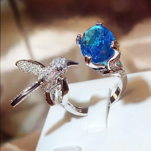 Detail of hummingbird ring with a large blue oval gemstone and pavé stones