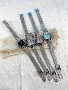 Group shot of four square dial women watches with mesh metal straps on lace background