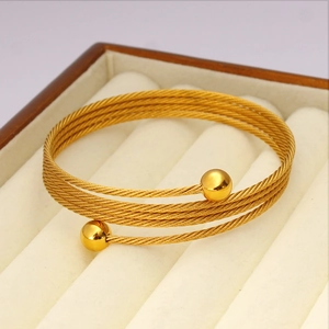 Dettaglio del bracciale multifilo in filo d'acciaio dorato su velluto bianco