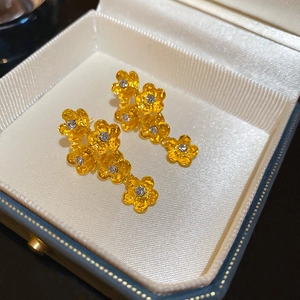 Detailed macro of golden flower pendant earrings with sparkling zircon centers on jewelry box