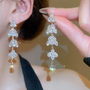 Detailed view of shimmering leaf tassel earrings with clear cubic zirconia in gold plating