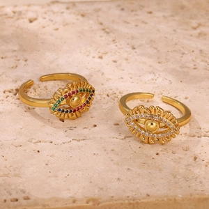 Macro view of gold devil's eye open rings with multicolored rhinestones on stone background
