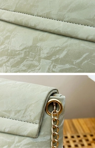 Détail du sac selle vert clair plissé avec coutures soignées et chaîne dorée