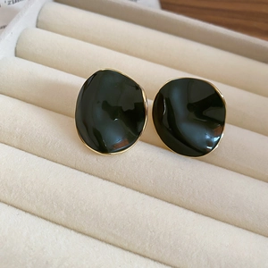 Detail of irregular black enamel earrings with gold plating in a cream velvet jewelry box