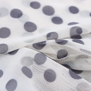 Detailed close-up of white mesh fabric featuring elegant grey and black polka dot patterns