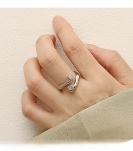 Detail of silver hugging hands open ring showing intricate palm and finger textures