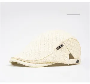 Close-up of cream straw ivy cap featuring herringbone weave and metal brand logo detail