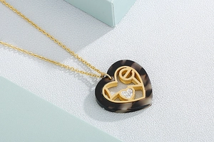 Detail of a heart-shaped tortoiseshell resin pendant with gold openwork and zircon inlay