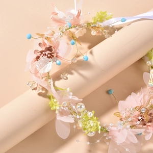 Macro shot of pink silk flowers, golden metal butterflies and faux pearls on the headpiece