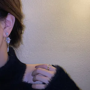 Detail of elegant teardrop zircon earrings and a delicate ring worn on a model