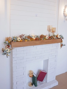 Autumn wreath with white pumpkins and warm LED lights on a white fireplace mantel