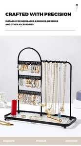 Detail view of multi-layer black metal jewelry rack for earrings and necklaces with a tray