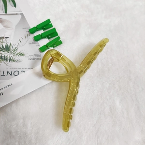 Close-up of amber translucent claw clip with gold spring on a soft white plush surface