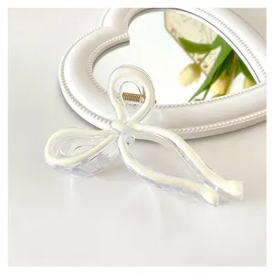 Detail shot of a 11cm bow hair claw clip in creamy white finish on a stylish background