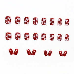 Short cherry red press-on nails with white heart and dot patterns for a New Year look