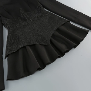 Detail der Taillierung mit Pailletten und Rüschen an einem schwarzen Langarmkleid