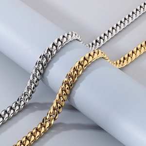 Close-up of 12mm silver and gold Cuban curb chains on a blue display pedestal