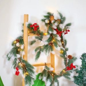 Artificial Christmas garland with pine needles berries and LED lights on a wooden ladder