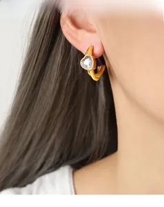 Dettaglio di orecchino a cerchio a U dorato con zircone a cuore su una modella