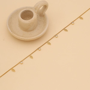Detailed close-up of golden leaf and circular rhinestone charms on a link chain necklace