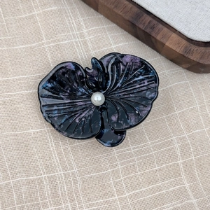Detail of elegant acetate orchid hair clip with purple marble pattern and faux pearl