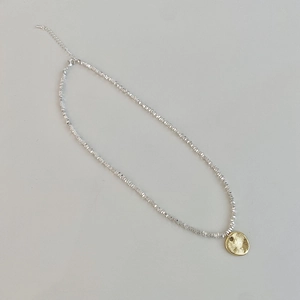 Macro view of gold pendant necklace with sparkling silver-tone crushed beads