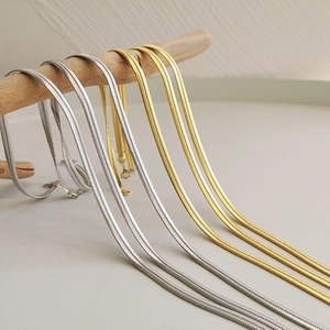Close-up of minimalist gold and silver snake bone necklaces hanging on a wooden stand