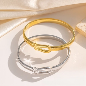 Macro detail of minimalist U-shaped horseshoe buckle bangles in gold and silver finish