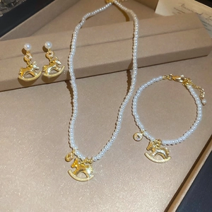 Detail of pearl jewelry set featuring gold pony pendants on necklace, bracelet and earrings