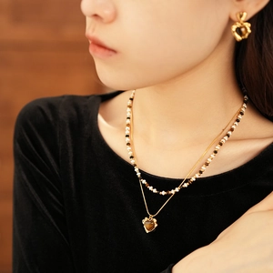 Detail of gold layered necklaces with tiger eye heart pendant and matching bead chain