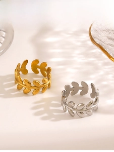 Detailed view of leaf-shaped open rings in gold and silver finish on a clean background